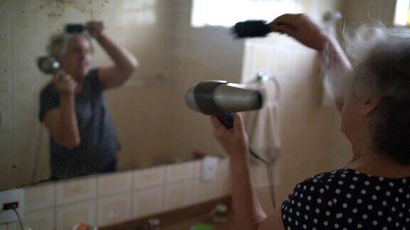 一位年长的女士在浴室吹干她的头发
