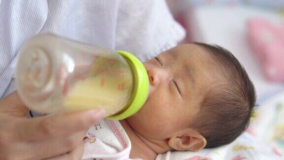 母亲抱着新生儿用奶瓶喂母乳