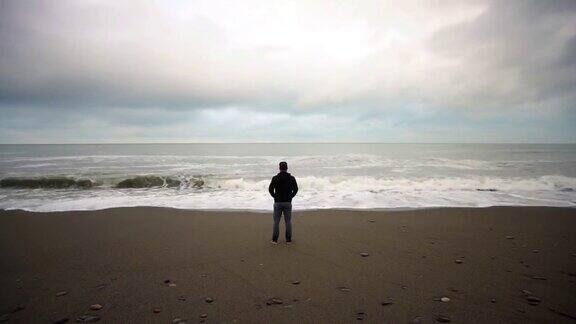 一个男人站在海滩上阴天大浪时间流逝