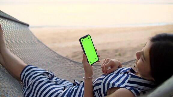 女人放松和使用手机绿色屏幕的海滩海滩