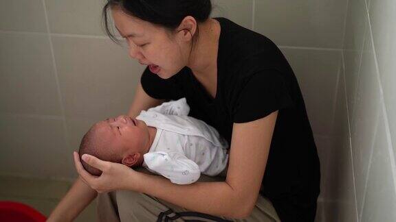 亚洲妇女正在浴室为她的宝宝洗澡