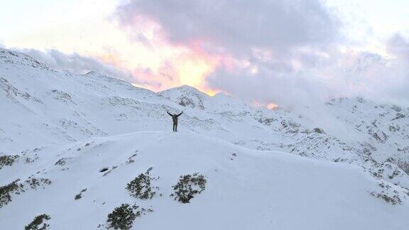 空中的冬季登山运动员胜利地把手举到山顶上