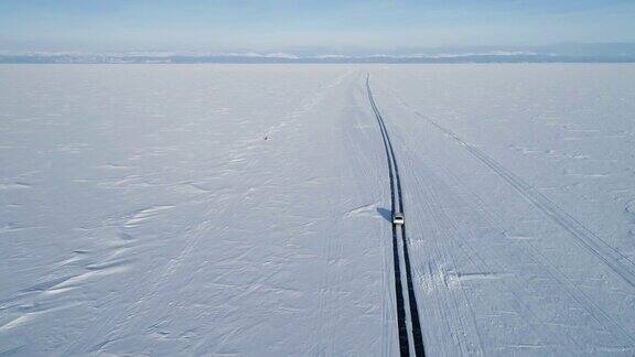 无人机跟踪一辆在冰上行驶的汽车美丽的冬天的风景