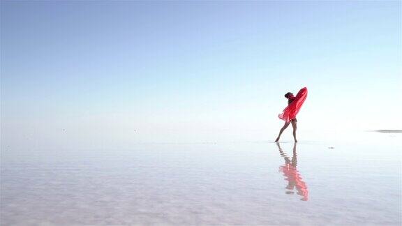 美丽的芭蕾舞演员在湖上用红色薄纱跳舞