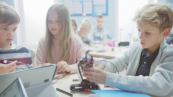小学机器人课堂:由聪明的孩子们组成的多元小组制作和编程机器人团队交流和工作孩子们学习软件设计和创造性机器人工程