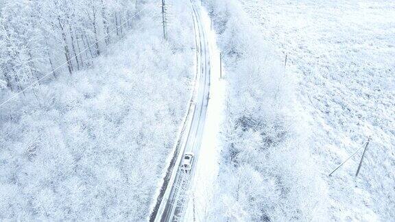 汽车在白雪覆盖的森林周围行驶的鸟瞰图
