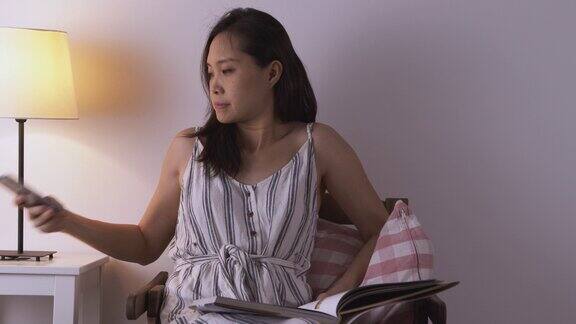 一个亚洲女人正在看书有人在客厅里叫她