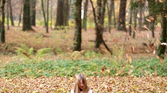 可爱的小女孩在公园里扔树叶打转
