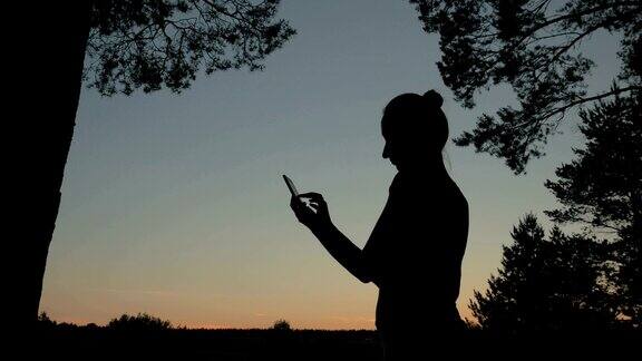 日落后在公园里用智能手机的女人