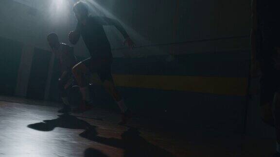 电影慢动作镜头的年轻的职业男性球员正在练习一个艰苦的篮球工作在一个健身房