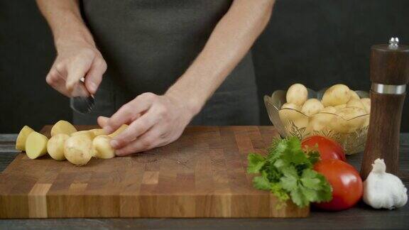 在厨房黑色的背景下男人在木板上切土豆