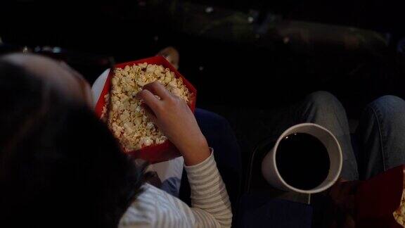 年轻的女孩在电影院一边看3D电影一边享受爆米花
