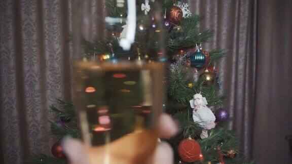 一个女孩举着一杯香槟在圣诞树的背景