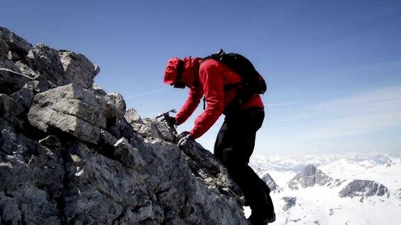 登山者爬过白雪覆盖的山上的岩石
