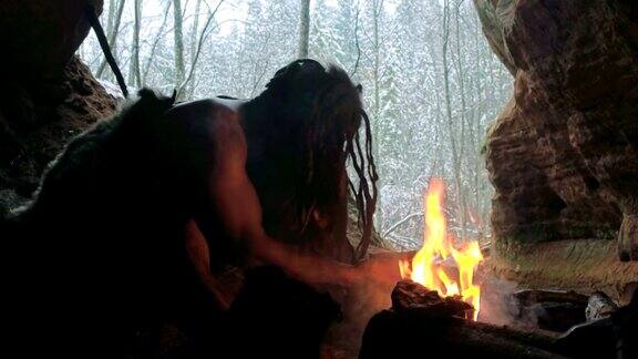 史前穴居人准备药剂或药物在他的洞穴在冬季森林的背景