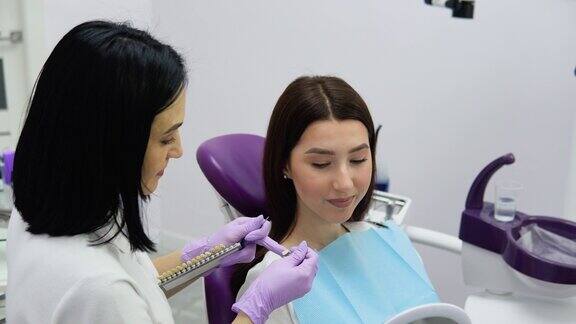 牙医从特殊的刻度选择牙齿颜色女孩病人和假牙的牙齿阴影选择