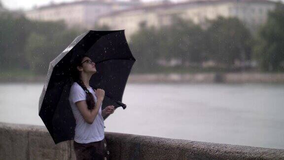 一个孤独的女孩站在雨中的伞下在河边想着一些事情