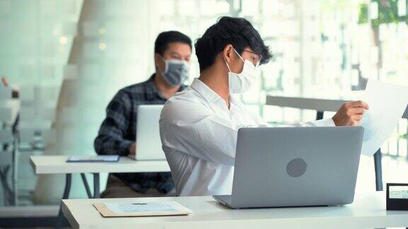 亚洲同事在新冠肺炎疫情期间戴着口罩上班