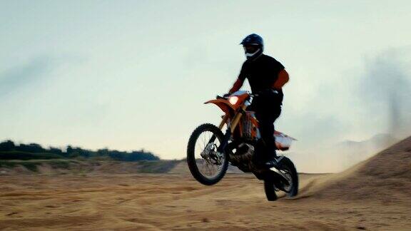 职业摩托车越野赛车手驾驶他的FMX摩托车在沙地越野赛道上越过沙丘