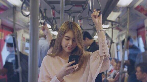 年轻的亚洲女子在火车上查看手机