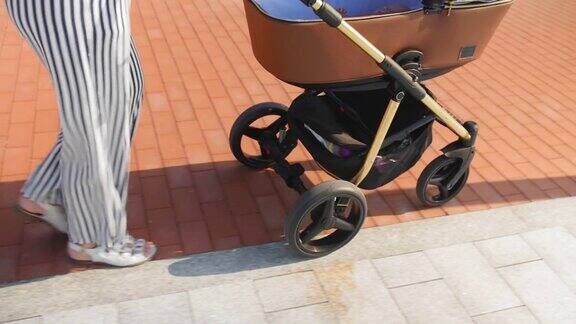 夏天散步时推着婴儿车、手推车、婴儿车;婴儿车前轮的特写镜头中景镜头