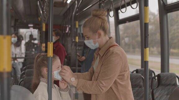 妈妈在公共汽车上给女儿戴口罩