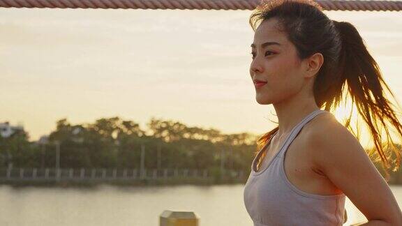 亚洲年轻美丽的女人在傍晚的夕阳在大桥在公共公园跑步健康运动员健康和坚定的女孩锻炼通过慢跑锻炼户外运动为她的健康