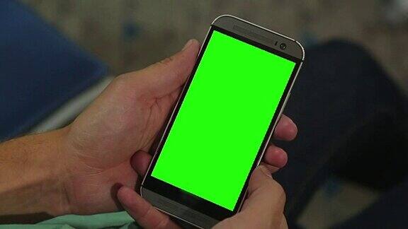 男性手持绿色屏幕智能手机的特写