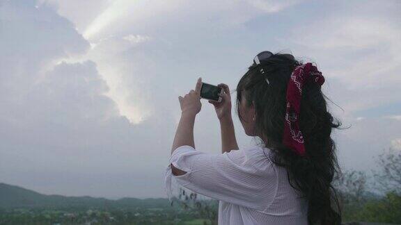亚洲旅行者摄影师女性在泰国拍摄日落的照片