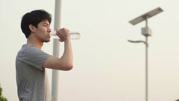 亚洲男子运动员在城市跑步后喝水