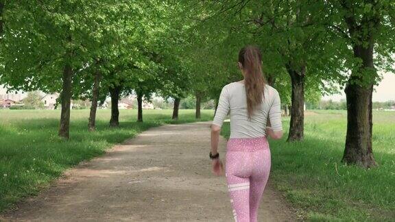 年轻的运动女性在公园里散步看手表的时间