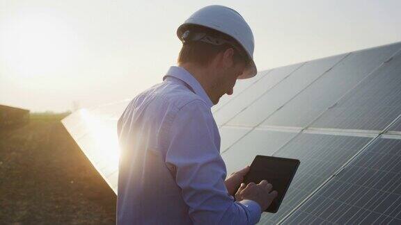 日落时分一名年轻的工程师正在用平板电脑检查太阳能光伏板场地的阳光和清洁情况理念:可再生能源、技术、电力、服务、绿色、未来