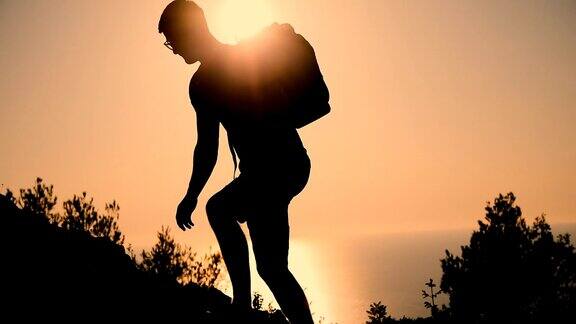 一个背着背包的男人在日落时分爬上了山顶日落时那个人的剪影健康积极的生活方式