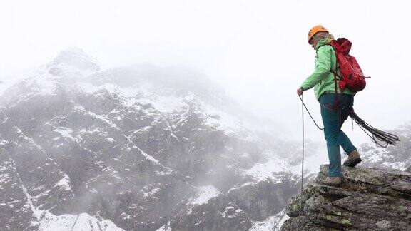 女登山家向外抛绳进行绳降(滑降)