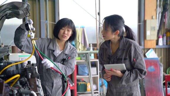 两个女机械师一起在汽车修理厂工作