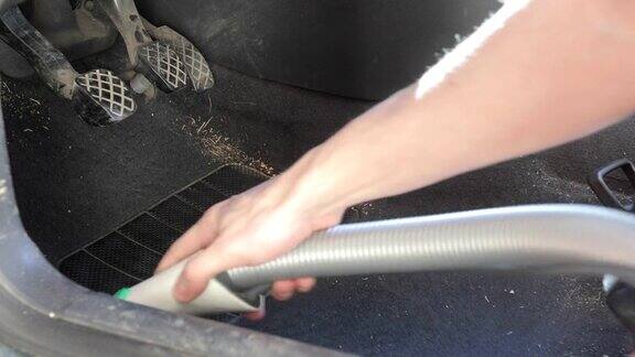 年轻人用吸尘器清扫汽车地板