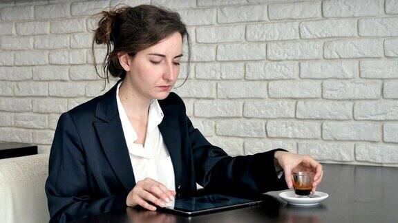 女商人一边喝咖啡一边用平板电脑iPad检查工作