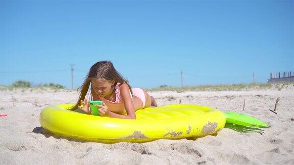 沙滩上可爱的小女孩躺在充气床垫上
