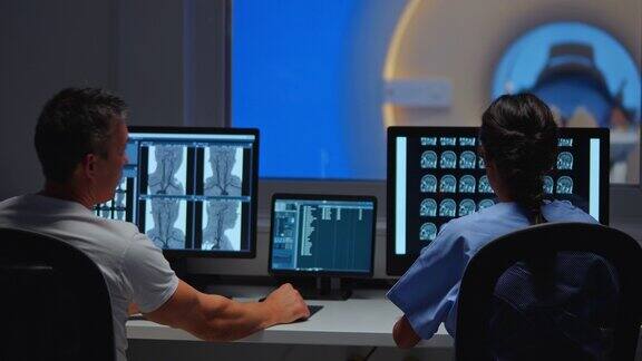 两名放射科医生在控制室看着电脑屏幕上的核磁共振图像