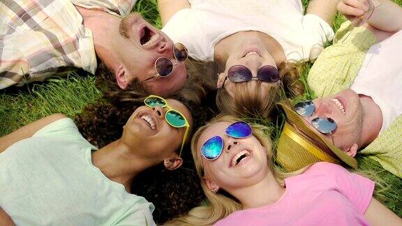 人们躺在草地上享受着生活笑着戴着太阳镜映着天空