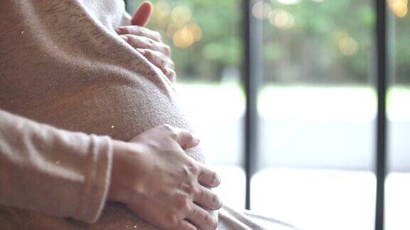 孕妇轻轻抚摸着肚子怀孕分娩