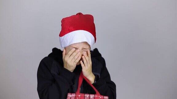 一个戴着圣诞老人帽子的男孩看了看礼物袋很沮丧