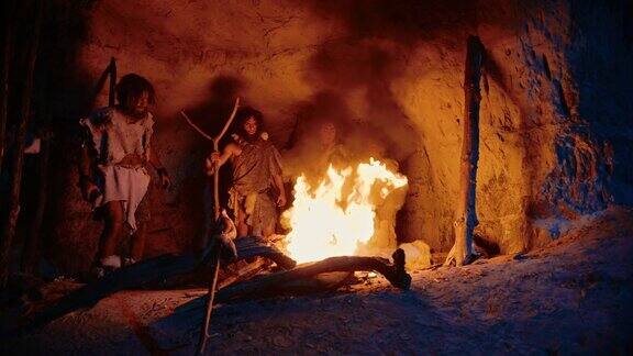 史前狩猎采集者部落穿着兽皮站在篝火外面的洞穴晚上尼安德特人智人家族在火旁进行异教仪式的肖像