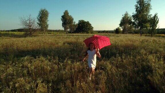 小女孩拿着红伞跑过田野