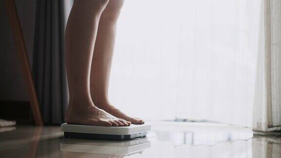 亚洲女性脚踩在数字体重秤检查她的体重称重秤