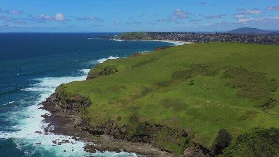 郁郁葱葱的绿草山丘与海岸悬崖相遇在晴朗的阳光下大海