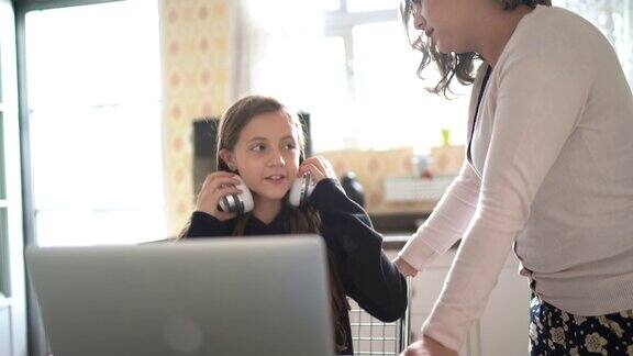母亲在家里帮助女儿做作业用笔记本电脑和女儿视频聊天