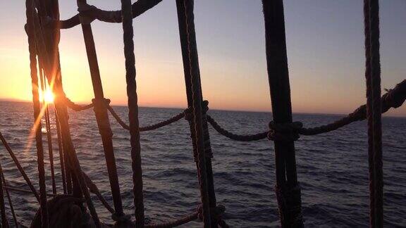 透过旧帆船的护桅索和索具看日落海景慢动作视频