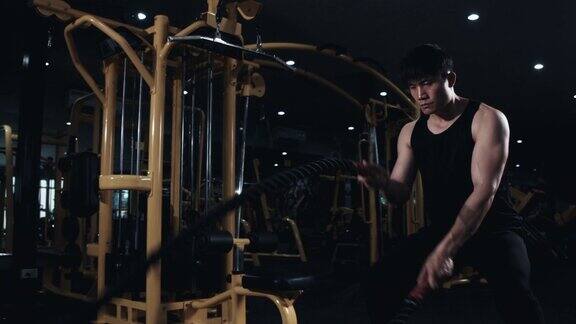 4K慢动作亚洲强人做战斗绳索练习在健身房在硬核健身房肌肉和运动员健美