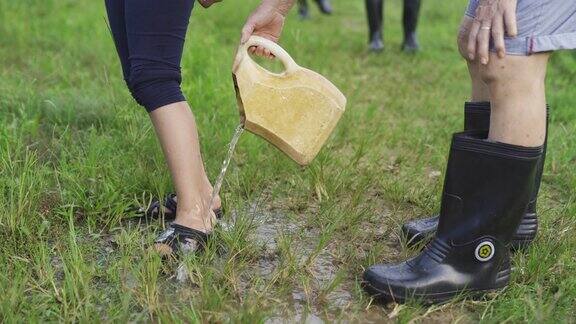 一位亚洲华人祖母在农场里给她的孙女泼水她的孙女在洗脚的时候沾上了泥